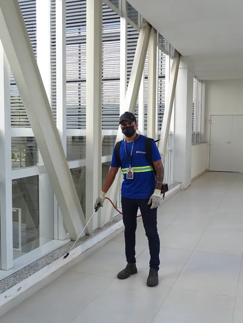 Técnico uniformizado da Desinsect com EPI em área comum de um prédio