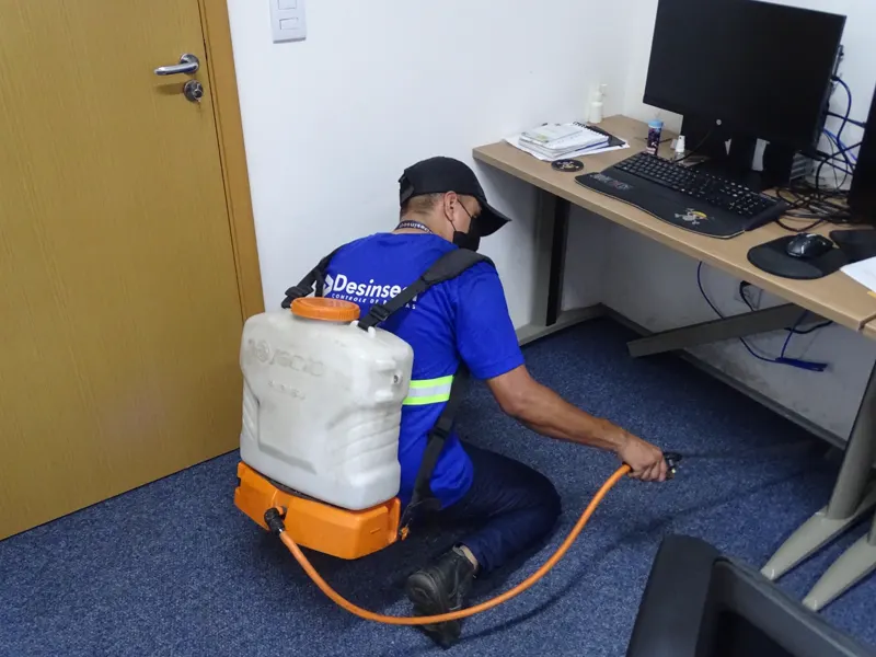 Técnico da Desinsect fazendo aplicação sob a mesa de um escritório
