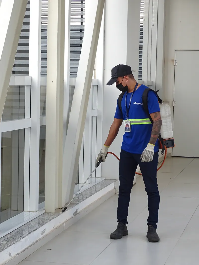 Técnico da Desinsect com pulverizador costal fazendo aplicação no rodapé